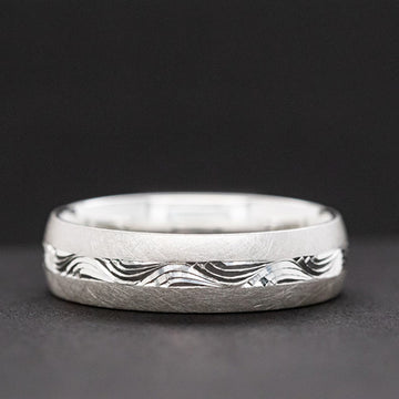 Silver ring with wave pattern on a dark background